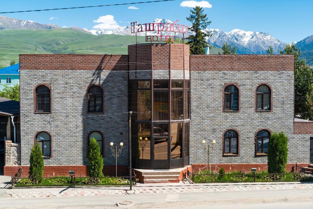 a brick building with a sign on top of it at Tashrabat Hotel in Karakol