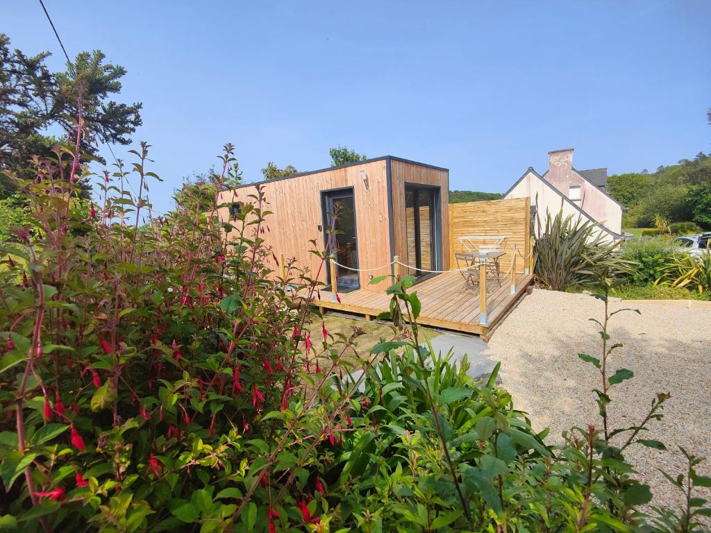 a small house with a deck in a garden at L'Escale in Penvénan