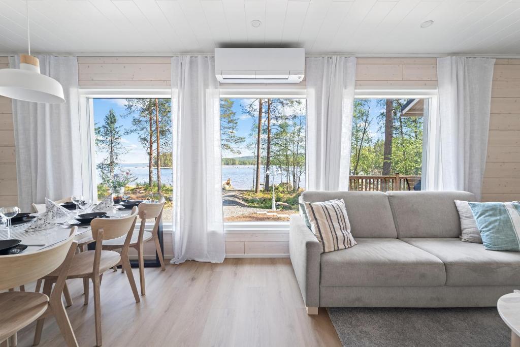 a living room with a couch and a table with a view at Villa Mustikkaranta Koli, oma ranta in Kolinkylä