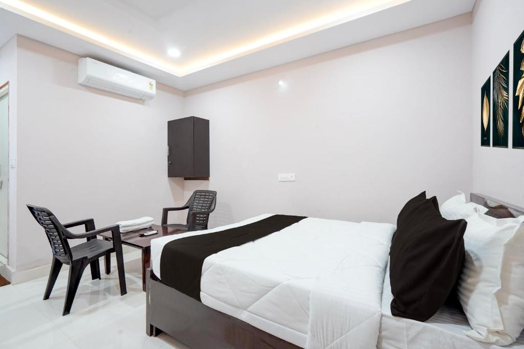 a bedroom with a bed and a desk and chairs at HOTEL O KMG GRAND in Bībīnagar