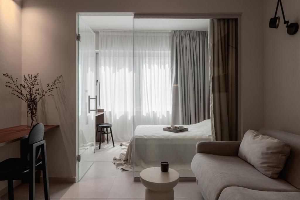 a bedroom with a bed and a living room with a couch at Sola District Volos in Volos