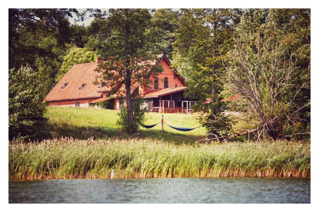 a house sitting on a hill next to a lake at Siedlisko Szwałk in Szwalk