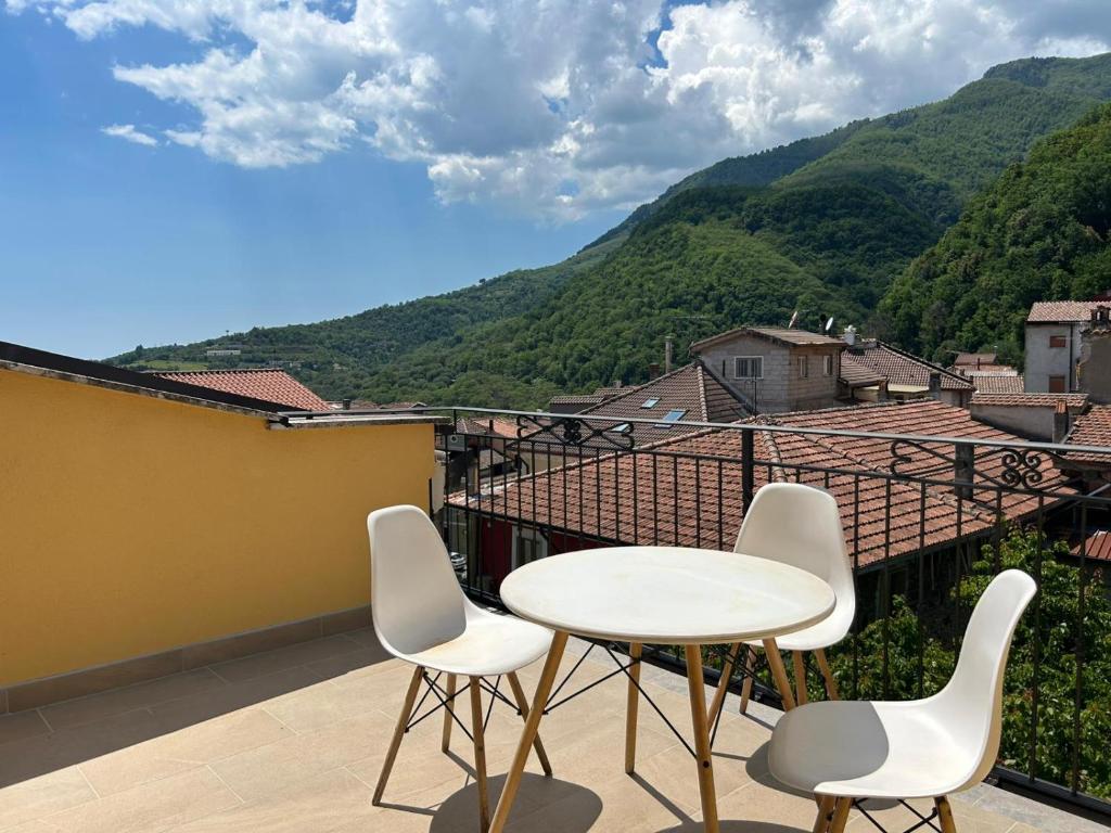 a table and chairs on a balcony with mountains at Affittacamere Point Concept Rooms in Laurito