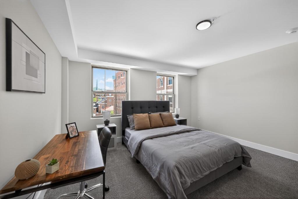 a bedroom with a bed and a table and windows at Elegant 2BR apartment with updated kitchen in Reading