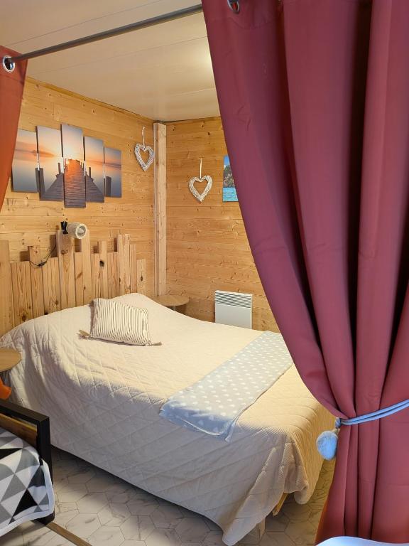 a bedroom with a bed with a red curtain at Studio bois avec jardinet in Parentis-en-Born