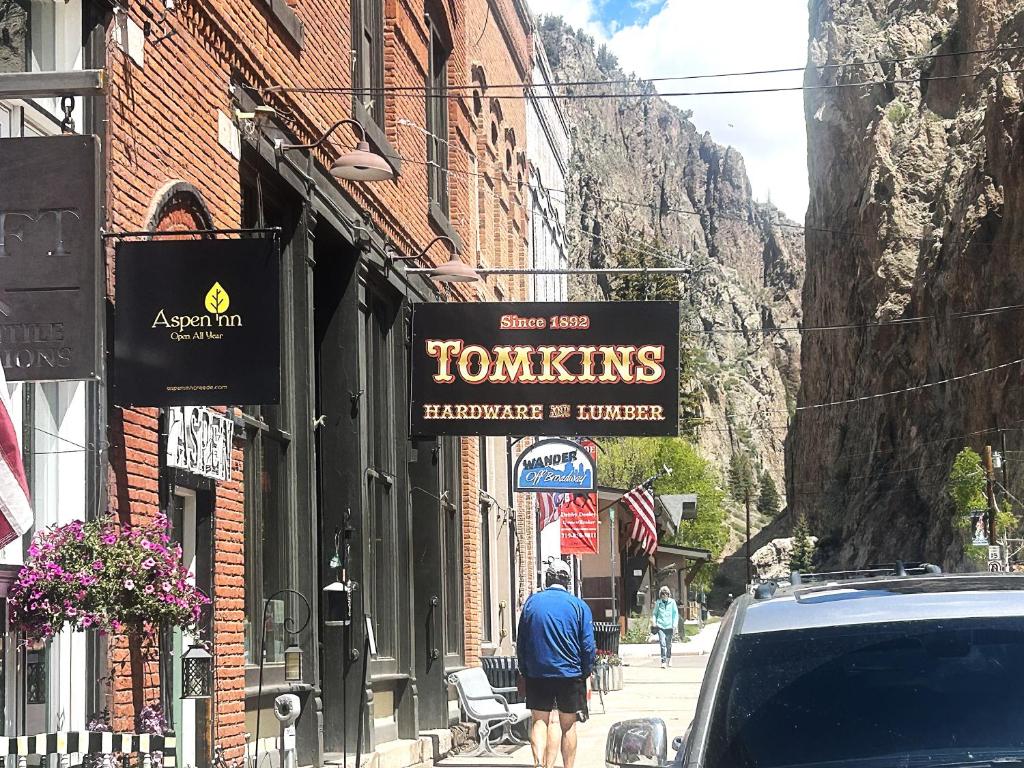 a man walking down a street with a sign that reads tomkins barbecue and burger at Aspen Inn in Creede