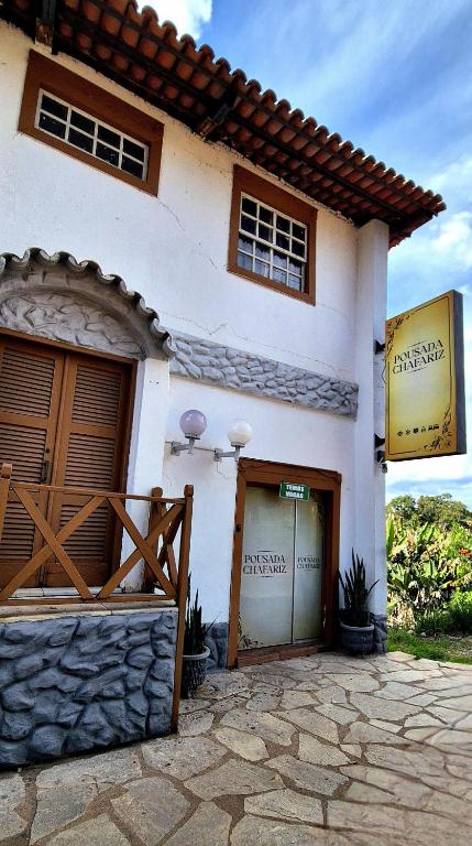 a white house with two garage doors and a gate at Pousada Chafariz in Pirenópolis