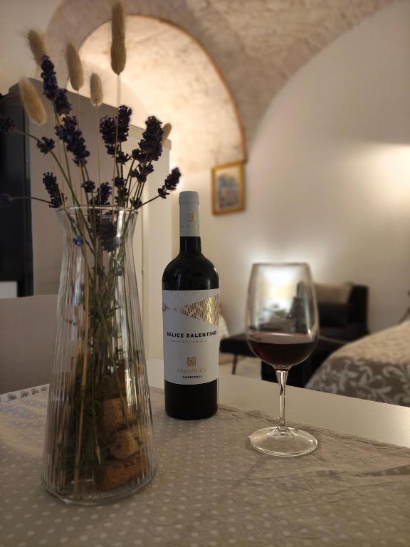a bottle of wine and a vase with a glass of wine at Casa Italiannebrasille in Castellana Grotte