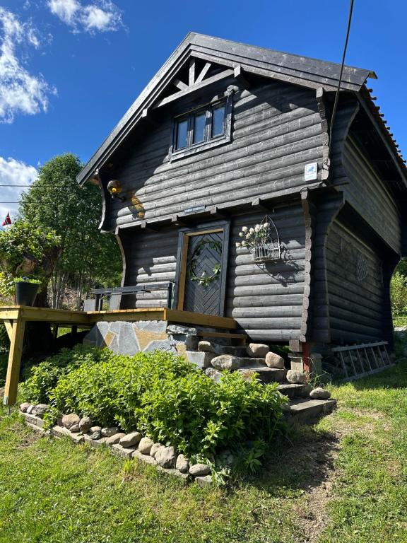a log cabin with a porch and a door at Stabbur Steinbekken Roost, Rustic Forest Stay, Shared Toilet, No Shower in Eidsvoll