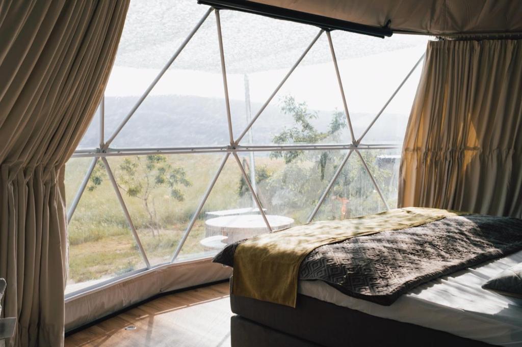 a bed in a room with a large window at Glamping-Steiermark in Pöllauberg