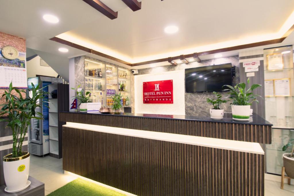 a lobby with a counter with potted plants at Hotel Pun Inn Kathmandu in Kathmandu