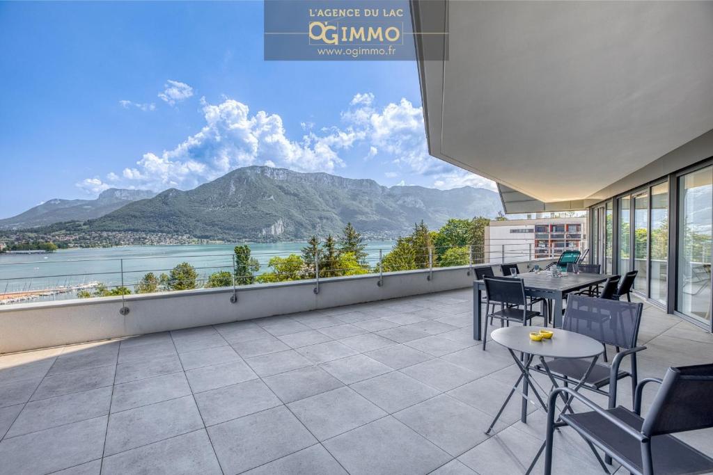 a balcony with tables and chairs and a view of a mountain at La Cantonade - Vue imprenable sur le lac Annecy in Annecy