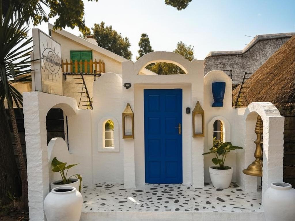 a white house with a blue door at Little Mykonos in Johannesburg