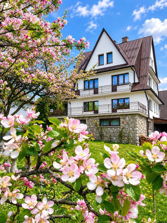 a house with pink flowers in front of it at Apartament Kułachówka - Sielskie wakacje na wsi, własny sad, pasieka i ogród in Leśnica