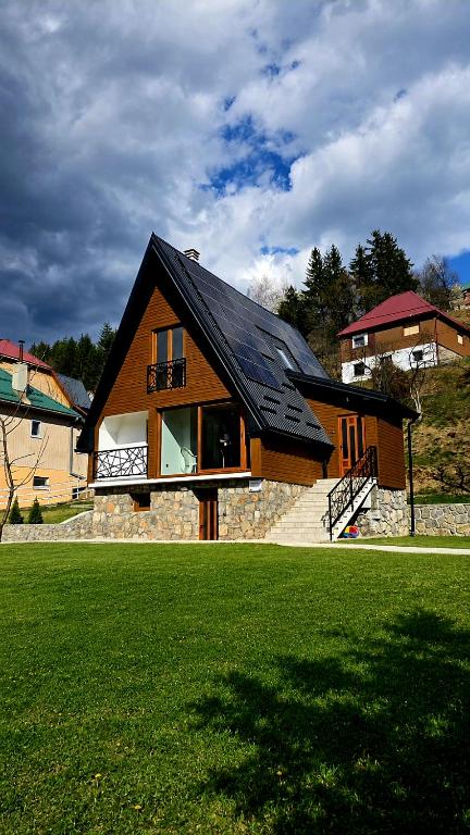 a house with a black roof on a green lawn at Mini Garden PREMIUM in Mojkovac