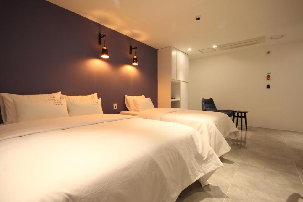 een slaapkamer met 2 bedden en witte lakens bij SOYU Hotel in Busan