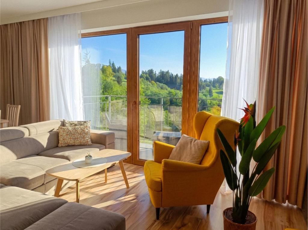 a living room with a couch and chairs and a large window at Apartamenty Kaniówka 25 in Gliczarów Górny