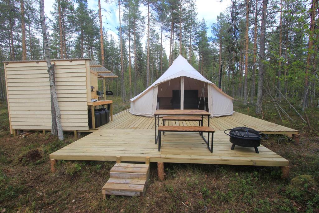 a tent with a table and a grill on a wooden deck at Stamsjö Glamp in Åsele