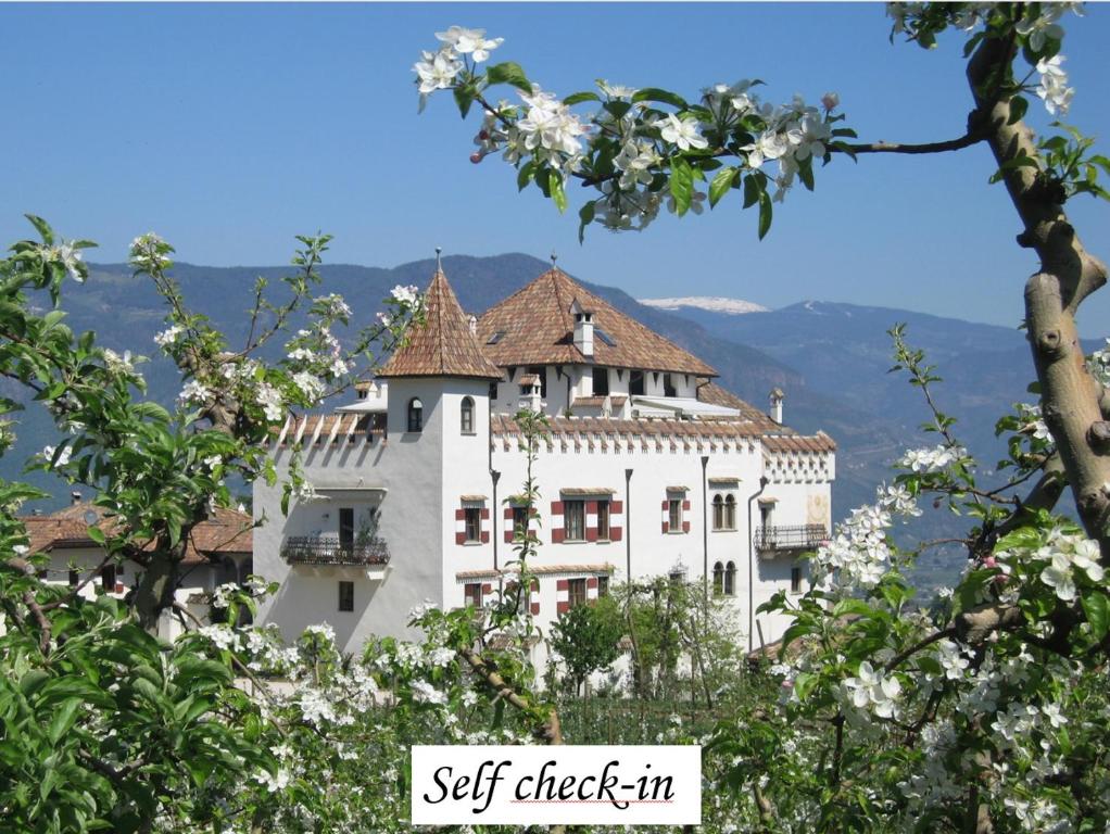 a white building with a tiled roof at Apartments Schloss Paschbach in Appiano sulla Strada del Vino