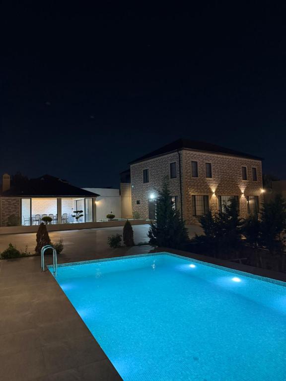 a swimming pool in front of a house at night at Novxanı Villa in Baku