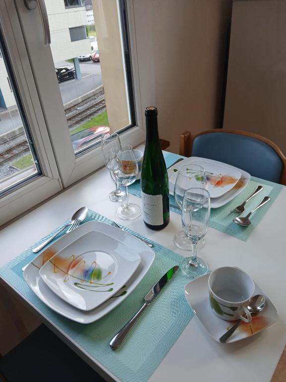 a table with plates and glasses and a bottle of wine at Zimmer mit Bad in Bühler