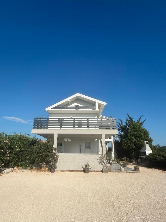 a white house sitting on top of a beach at Apartmani Fulir in Vrsi