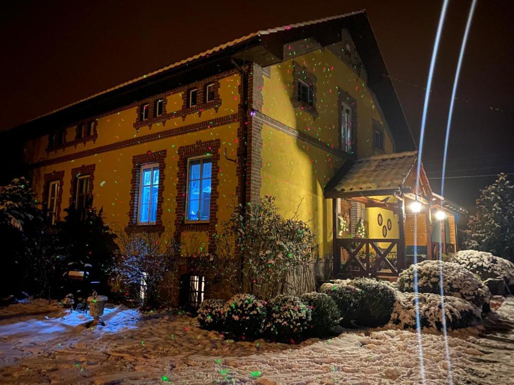 a yellow building with snow on it at night at B&B Stare Łysogórki in Stare Łysogórki