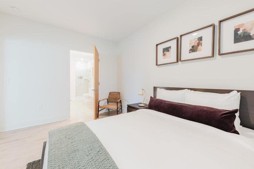 a white bedroom with a large bed and a chair at Joinery North in Charlotte