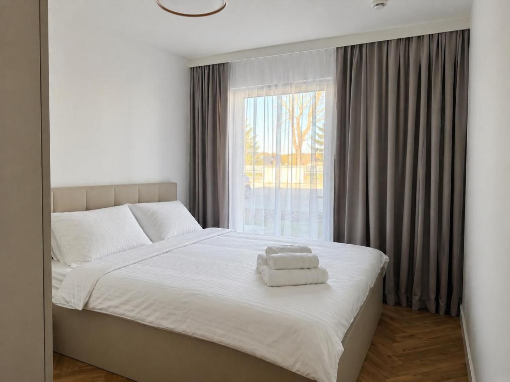a bedroom with a bed with white sheets and a window at Pino SeaView II in Gdańsk