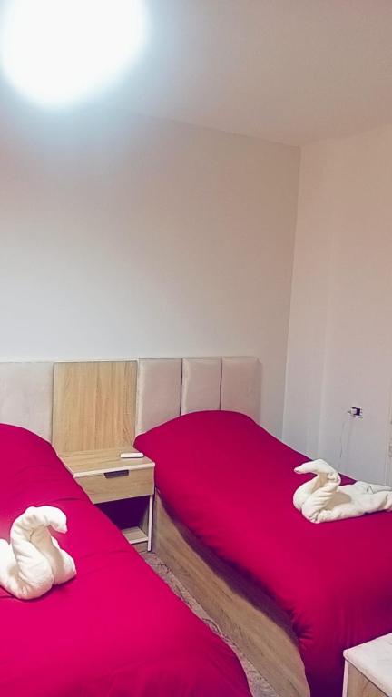 a bedroom with two beds with red sheets and a table at Karak Castle House in Kerak