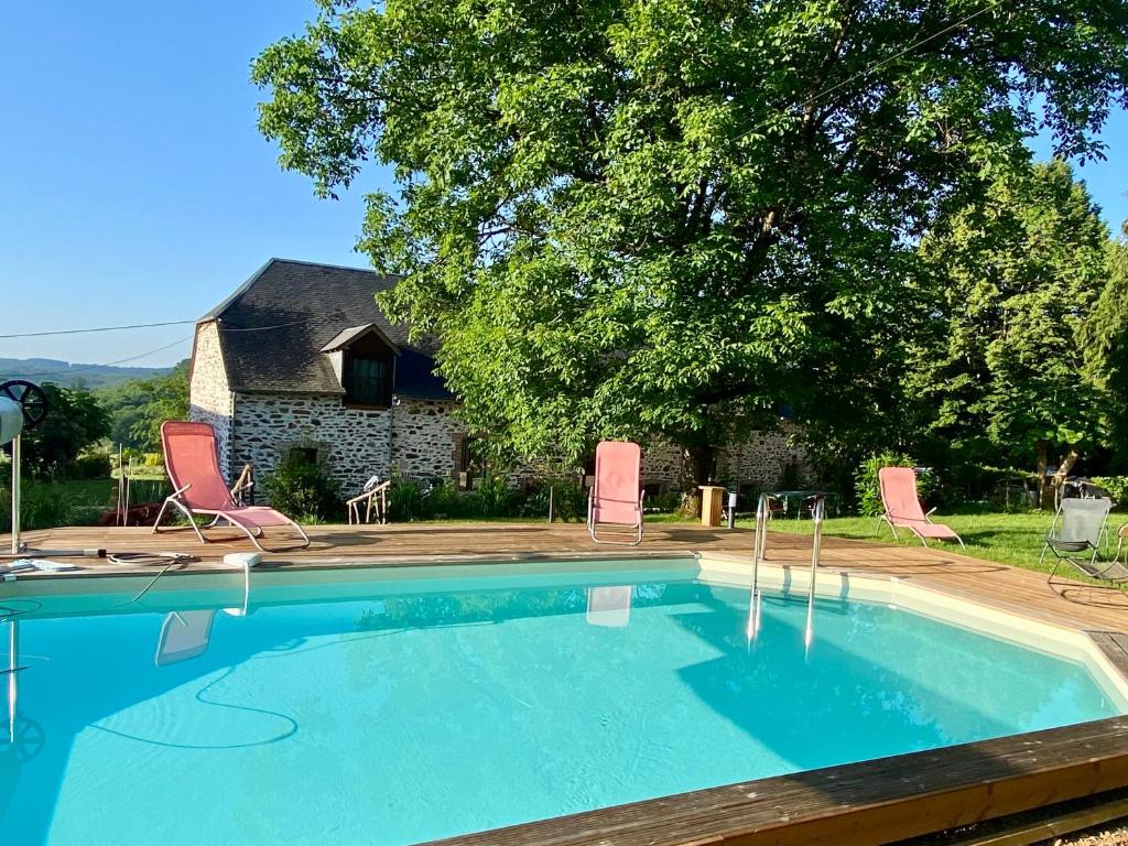 a swimming pool with chairs and a house at La grange de Moli in Vigeois