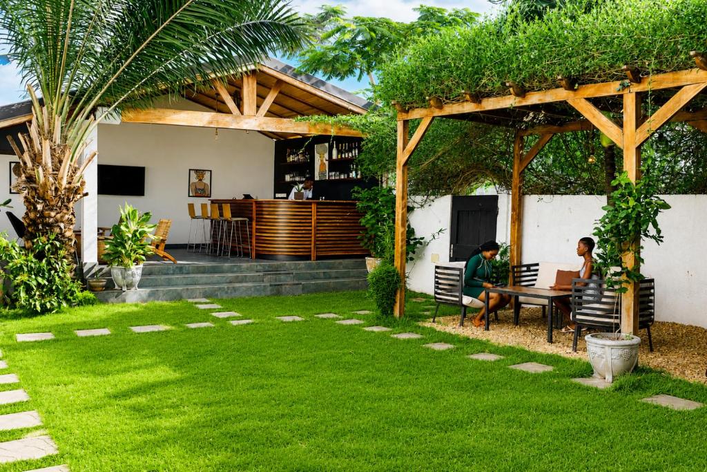 two people sitting at a table in a garden at Ahomé Guest house & Lounge in Lomé