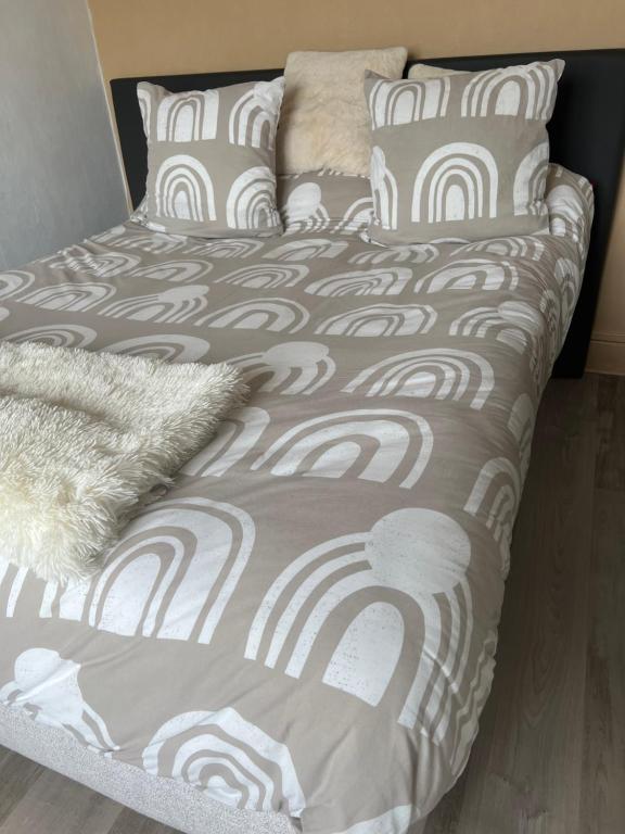 a bed with a gray and white comforter and pillows at Splendide, FACE MER avec place de parking PRIVEE in Berck-sur-Mer