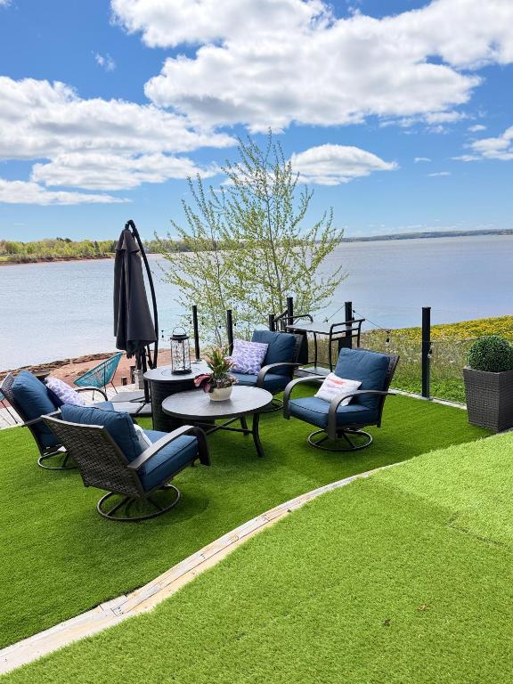 a group of chairs and tables on a lawn next to the water at luxury Beachfront Home With Private Beach Access in Charlottetown