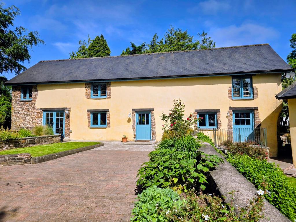 a yellow house with blue doors and a driveway at Pylemoor Cottage in Tiverton