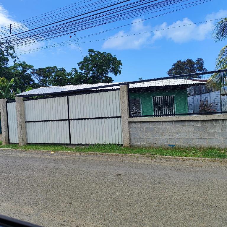 a white fence with a green window and a building at Casa KAFRA in Hone Creek