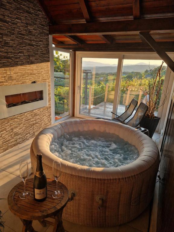 a large tub with a bottle of wine and two wine glasses at Vineyard Cottage with Private Jacuzzi in Metlika