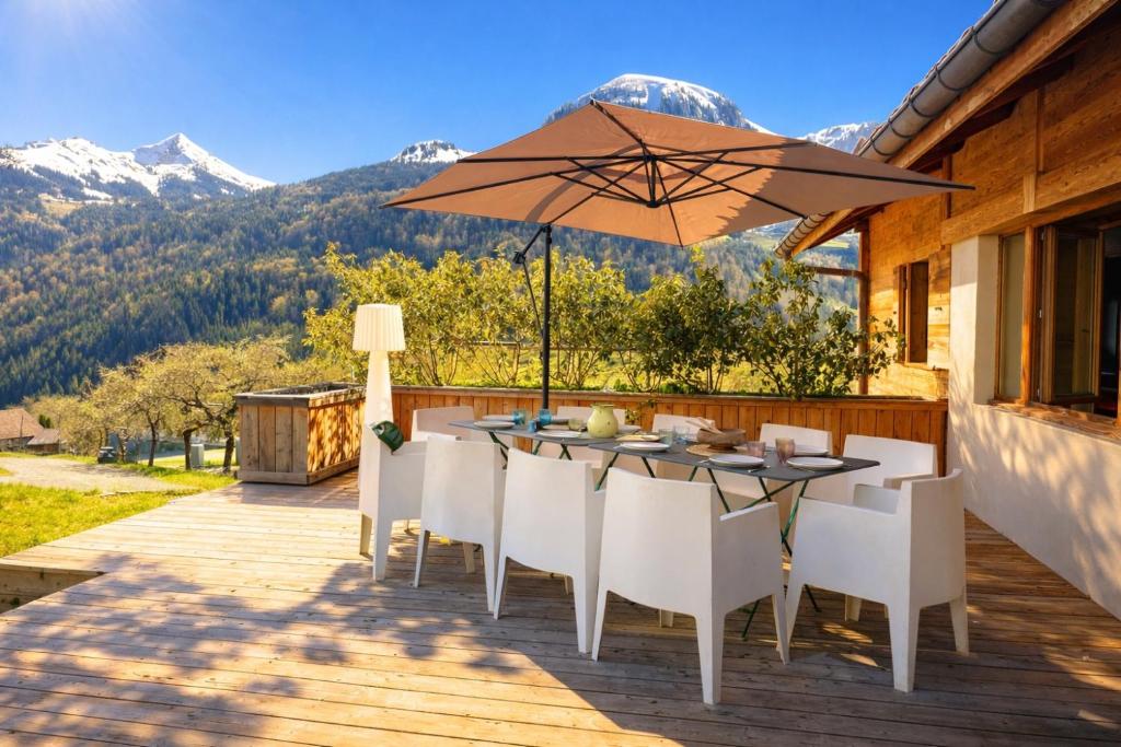 a patio with a table and chairs and an umbrella at chalet in authentic Manigod farm in Manigod