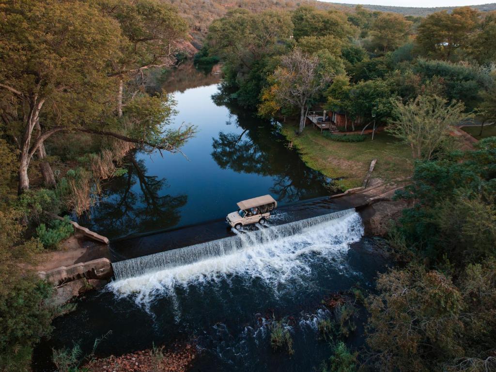 an aerial view of a truck driving over a waterfall at Mologa River Lodge in Rust de Winter