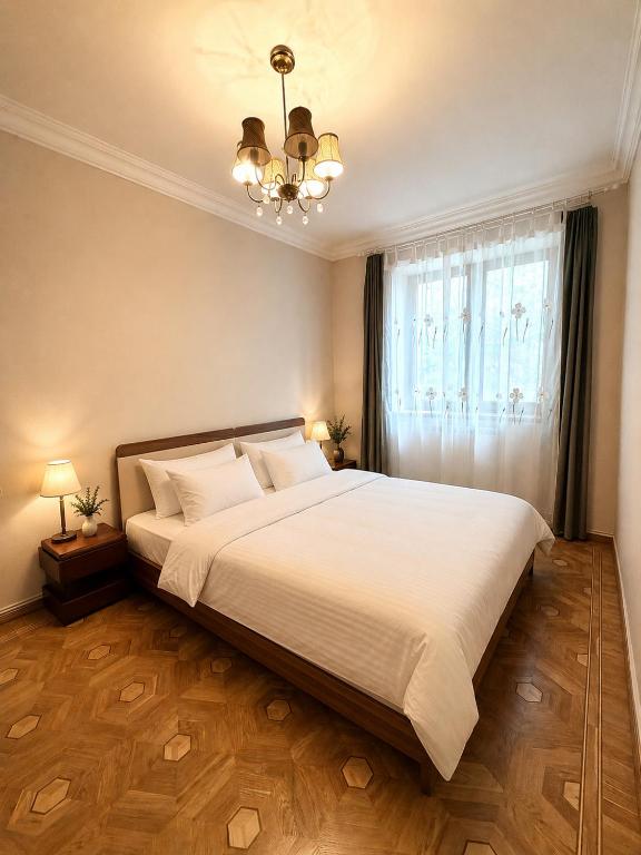 a bedroom with a large white bed and a chandelier at Nice Apartment in the City Center in Yerevan