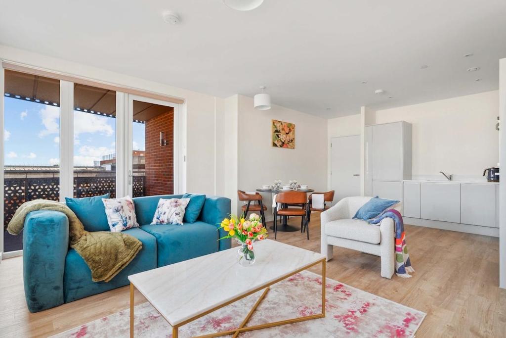 a living room with a blue couch and a table at Modern 2 Bedroom Flat with FREE Parking, Close to Heathrow and Thorpe Park in Staines