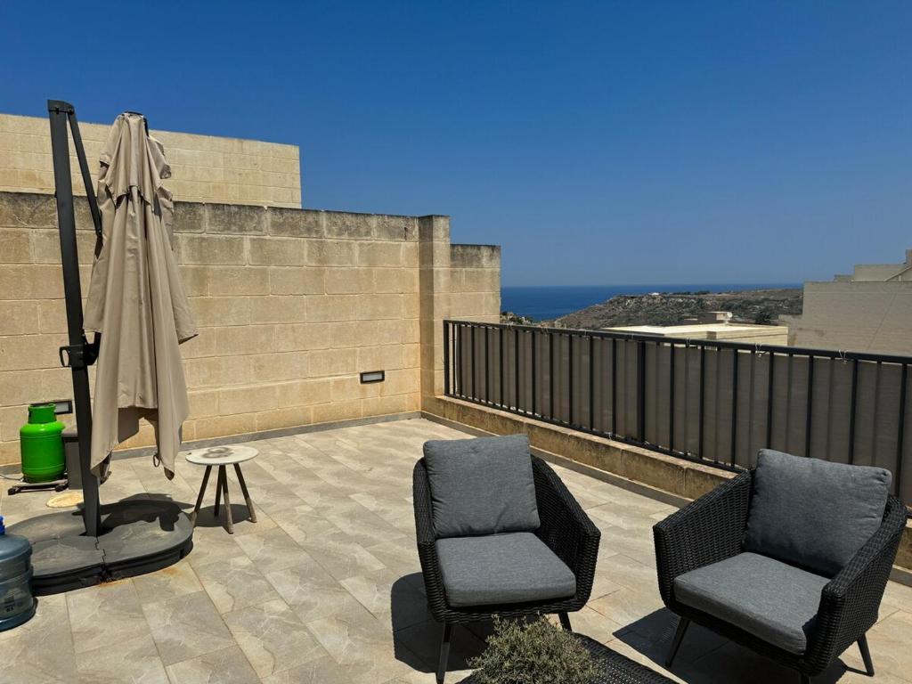 a patio with two chairs and an umbrella and an umbrella at Sea Views Penthouse Apartment in Xagħra