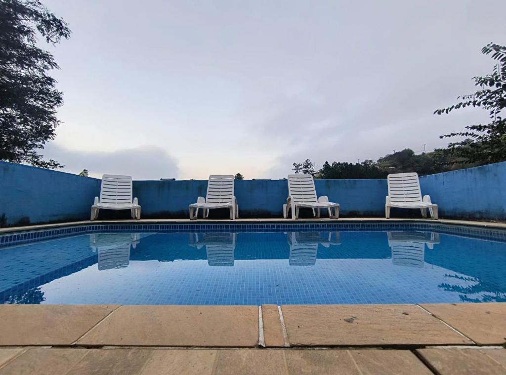 three chairs sitting next to a swimming pool at CHÁCARA dos CHEIROS in Atibaia