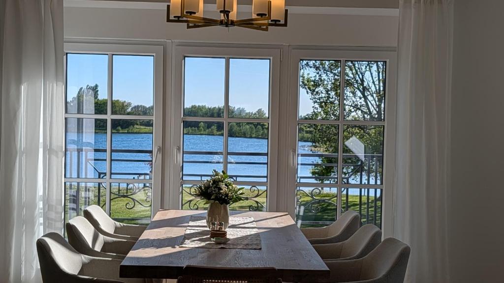 a dining room with a table and chairs and windows at Ferienwohnung Coproyshof - Direkt am See - 3 Schlafzimmer, privater Strand & Feuerstelle in Wesel