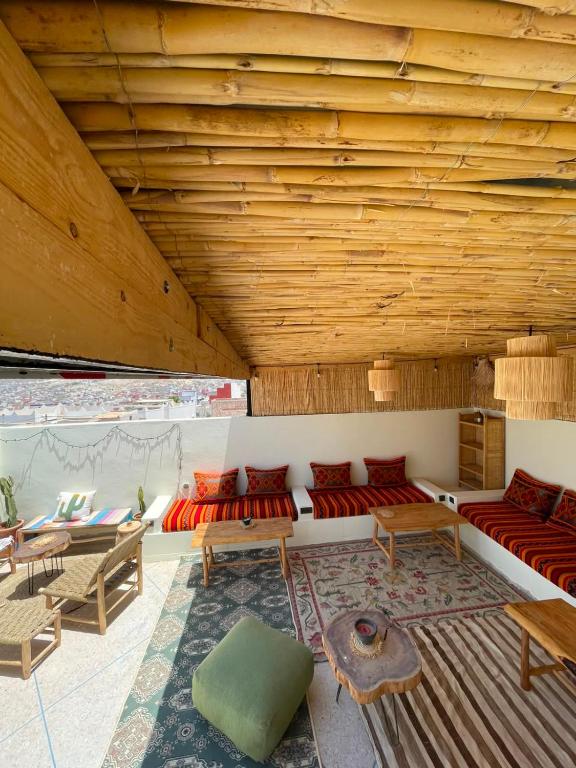 a living room with wooden ceilings and red couches at Coastal Haven Surf Morocco in Aourir