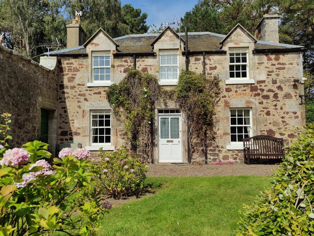 an old stone house with a bench in the yard at Newbyth Garden Cottage in East Linton
