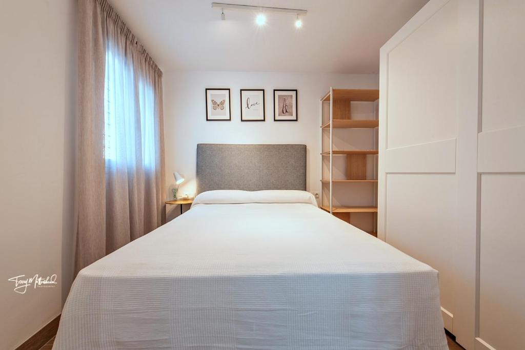 a bedroom with a white bed and a window at La Cepa Apartamentos in Alhama de Granada