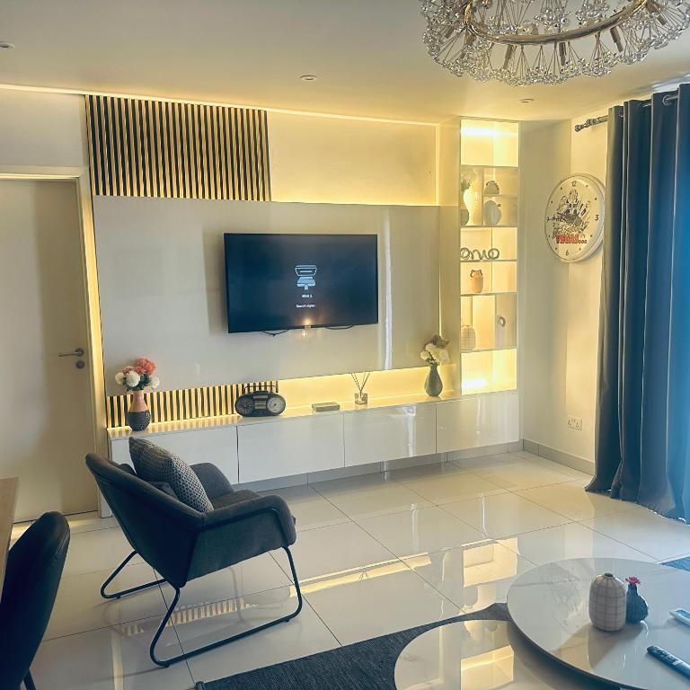 a living room with a tv and a chair and a table at Loxwood by Tripview Apartments in Accra
