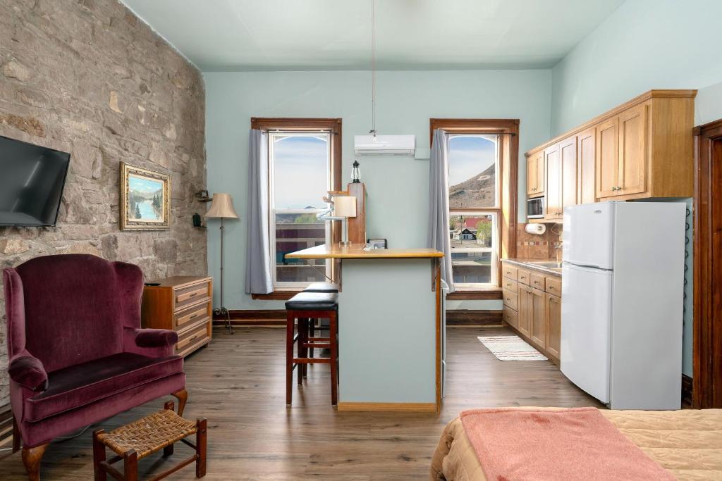 a kitchen with a refrigerator and a table and a chair at Del Norte Colorado Stone Quarry Studio Apt in Del Norte