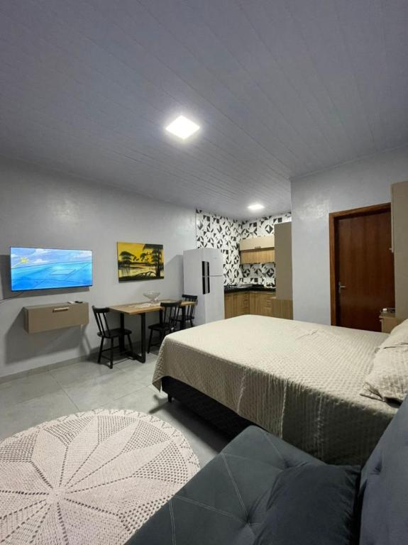 a bedroom with a bed and a kitchen with a table at Apartamento Açaí in Vilhena